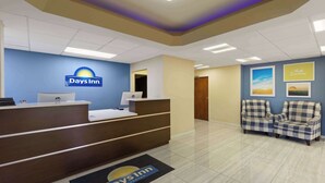A reception area with a blue wall, a reception desk, a laptop, and a chair. - Days Inn by Wyndham Oak Grove/Ft. Campbell (Oak Grove)