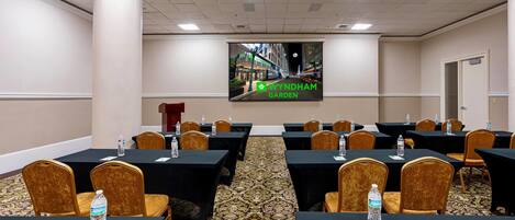 A conference room with tables, chairs, and a large screen displaying a cityscape.
