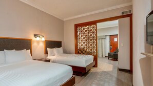 Una habitación de hotel con dos camas, cabecero de madera, lámpara de pared y separador de madera.