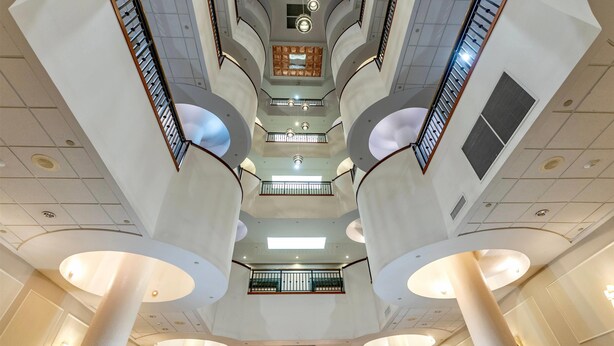 Un atrio de varios niveles con un espacio central abierto, varios pisos y un diseño arquitectónico moderno.