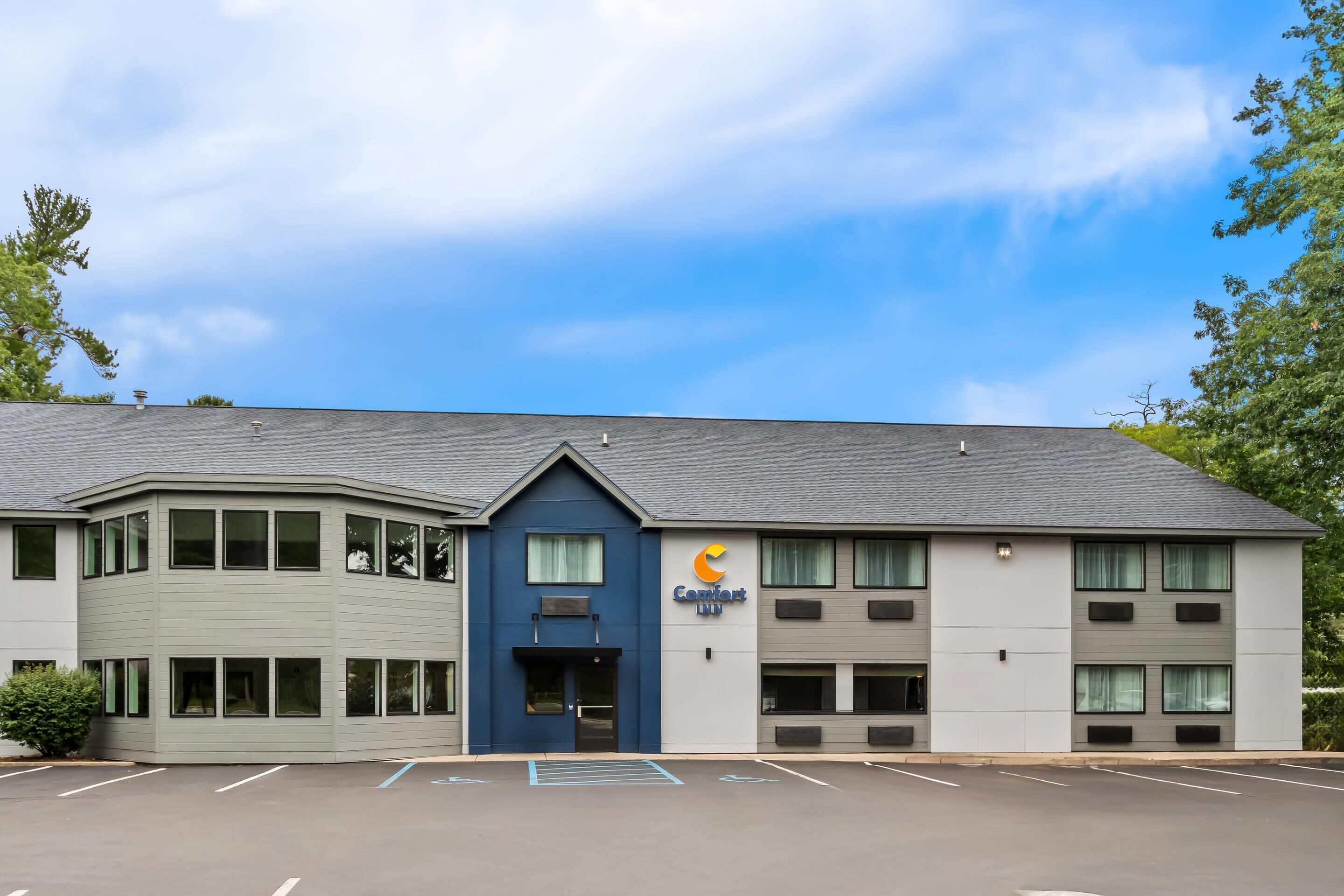 A Comfort Inn hotel with a modern design, featuring a parking lot and a clear sky.