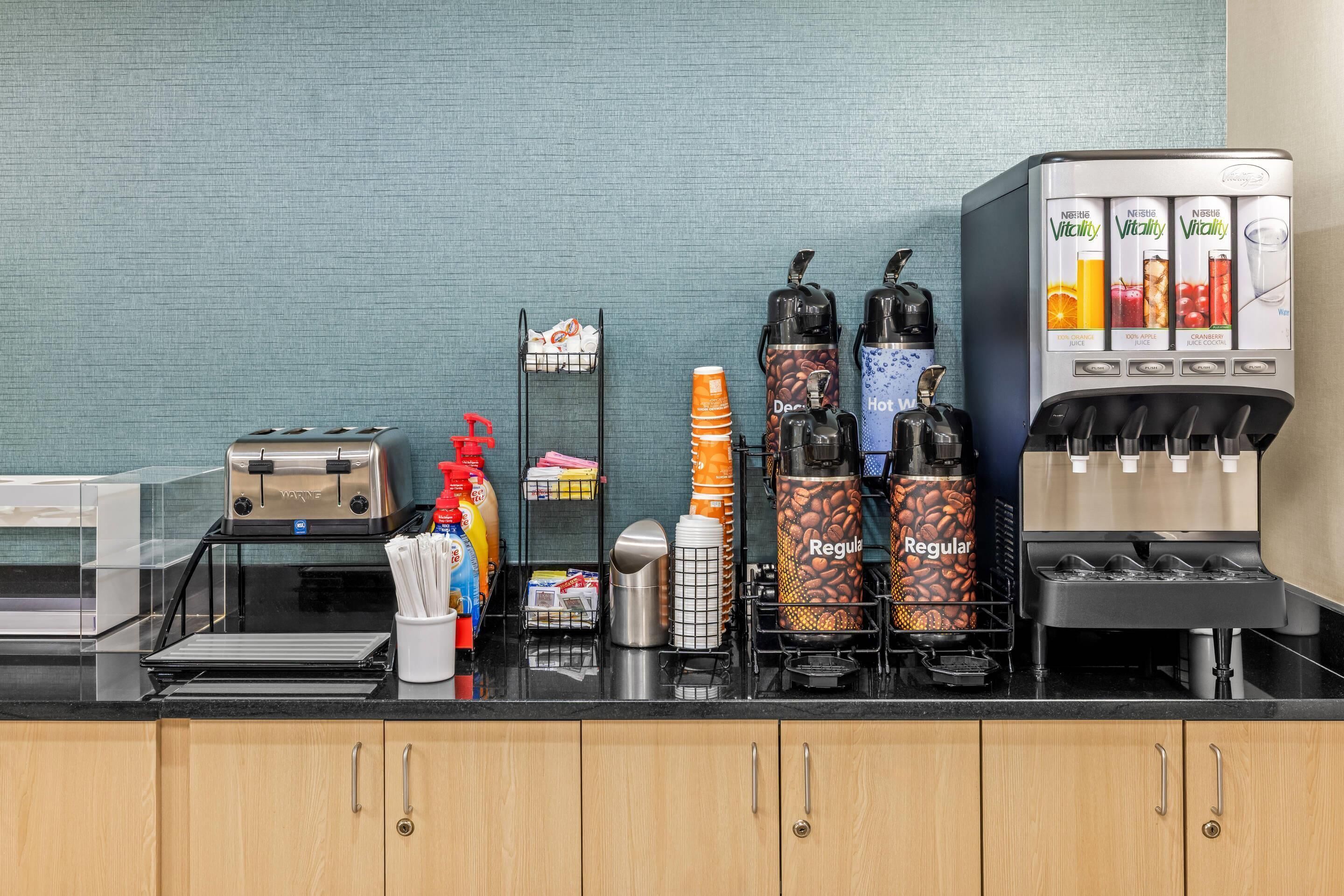 Una encimera de cocina con una cafetera, un tostador y varios tipos de cápsulas de café.