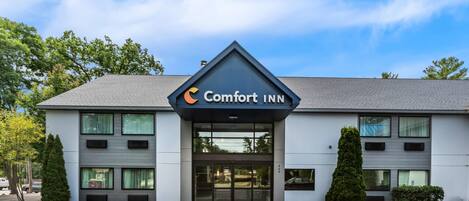 A Comfort Inn hotel with a modern design, featuring a prominent entrance and a parking lot.