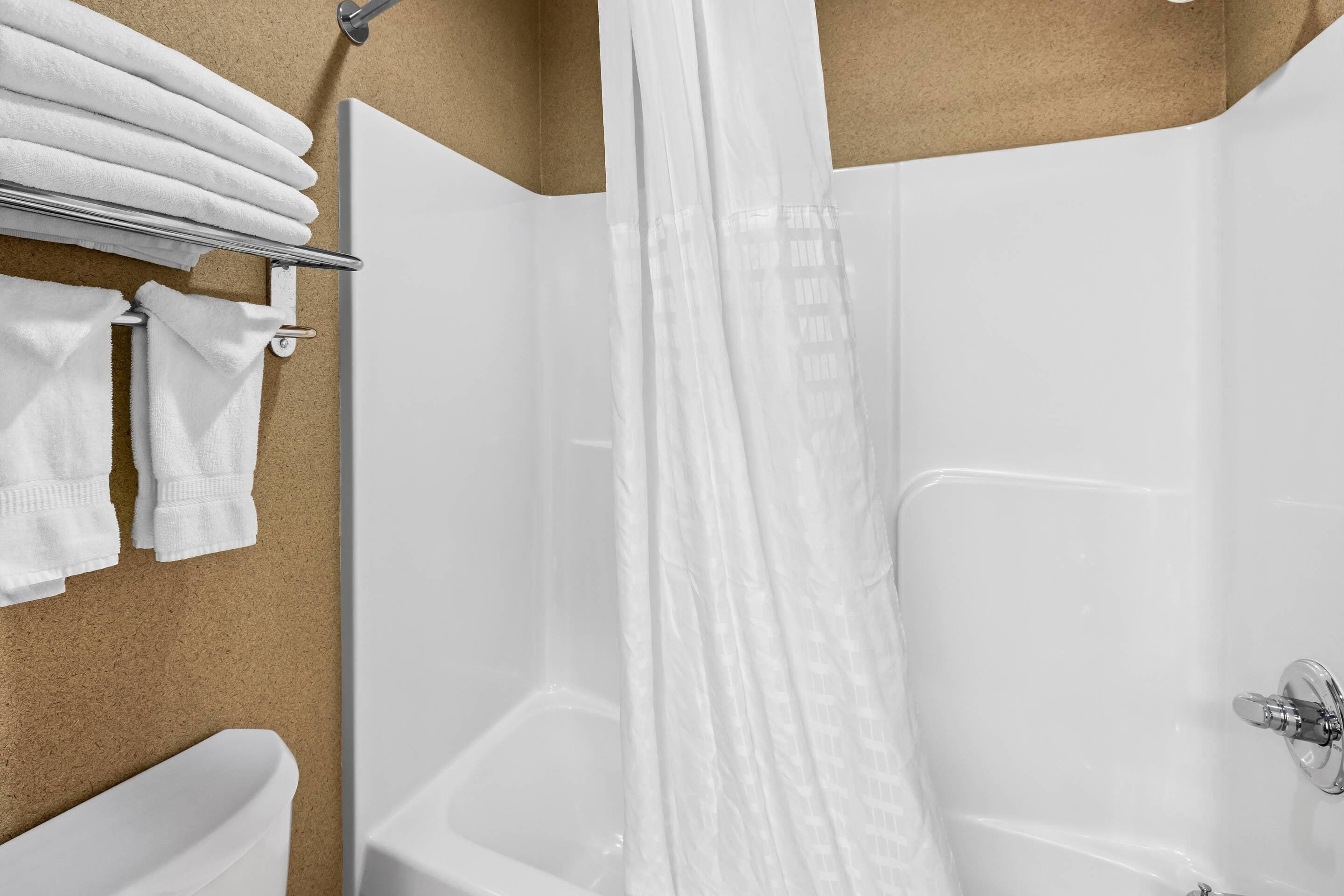 Un baño con una bañera, una cortina de ducha y toallas en un escurridor.