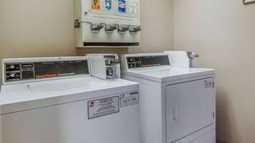Uma lavanderia com duas máquinas de lavar de abertura frontal e uma máquina de amaciante com moedas.
