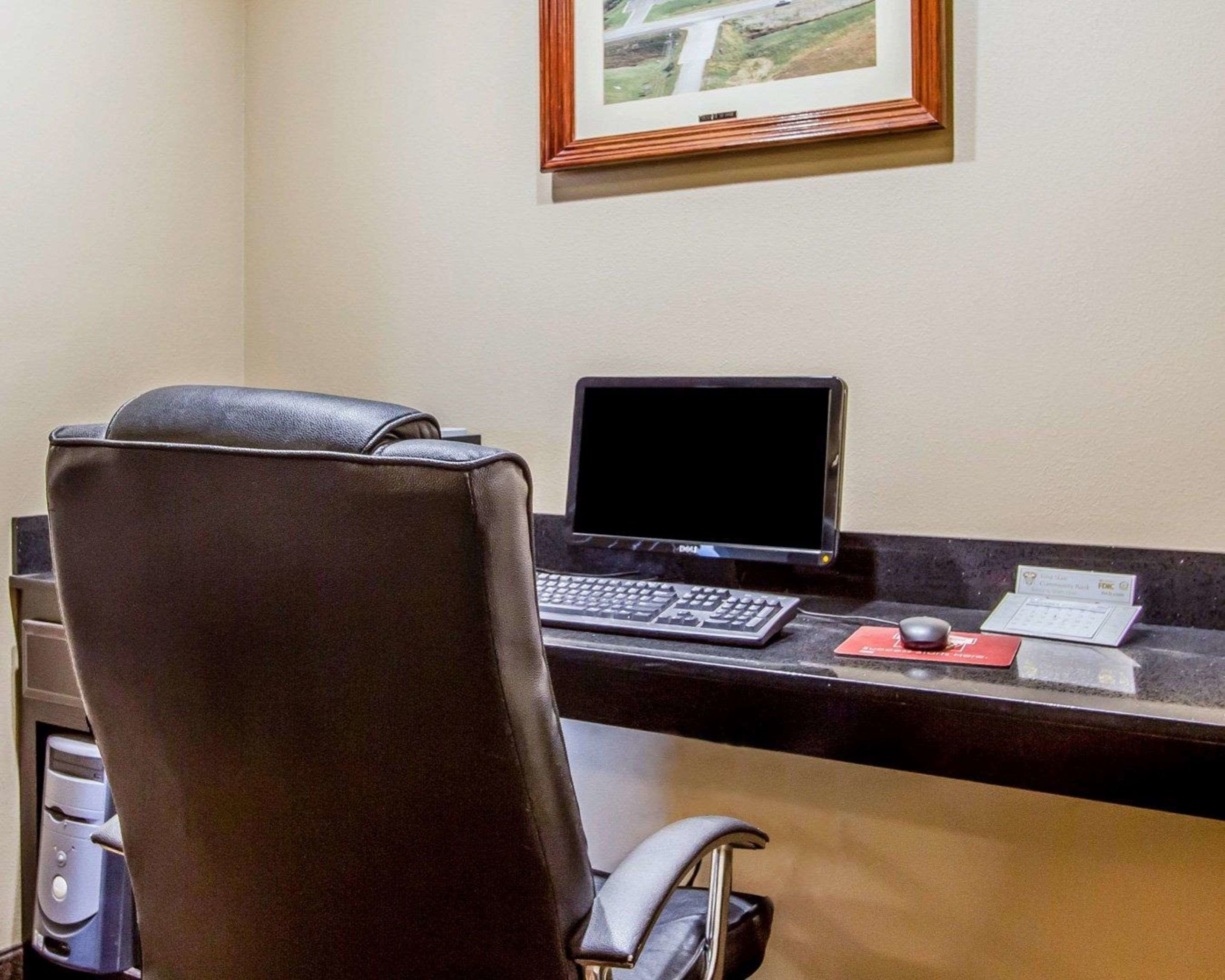 Una reception hotel con un computer, una tastiera, un mouse e un quadro incorniciato al muro.