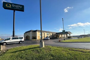 A Quality Inn by Choice Hotels with a clear sky, a parking lot, and a building entrance.