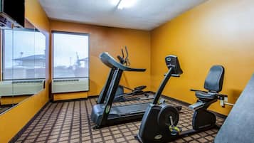 Een sportschool met loopband, elliptische trainer en hometrainer, een vloerbedekking en grote ramen met uitzicht.
