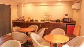 A small kitchenette with a microwave, coffee maker, and a fruit bowl. There are four chairs and a small table. - Days Inn by Wyndham Little River (Little River)