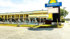 A Days Inn hotel with a swimming pool, outdoor seating, and a clear sky. - Days Inn by Wyndham Little River (Little River)