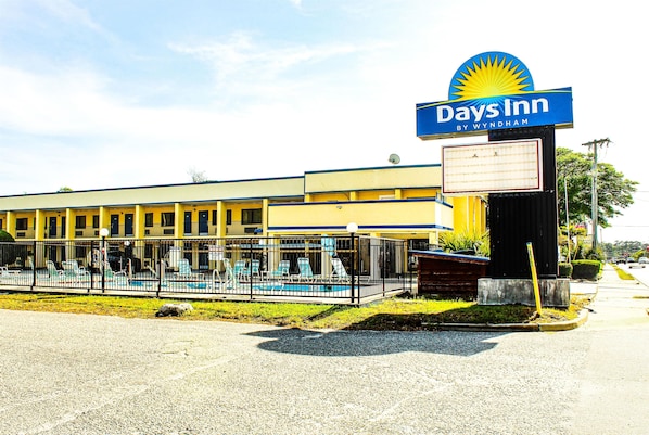 Um hotel Days Inn com piscina, área de estar externa e céu claro.