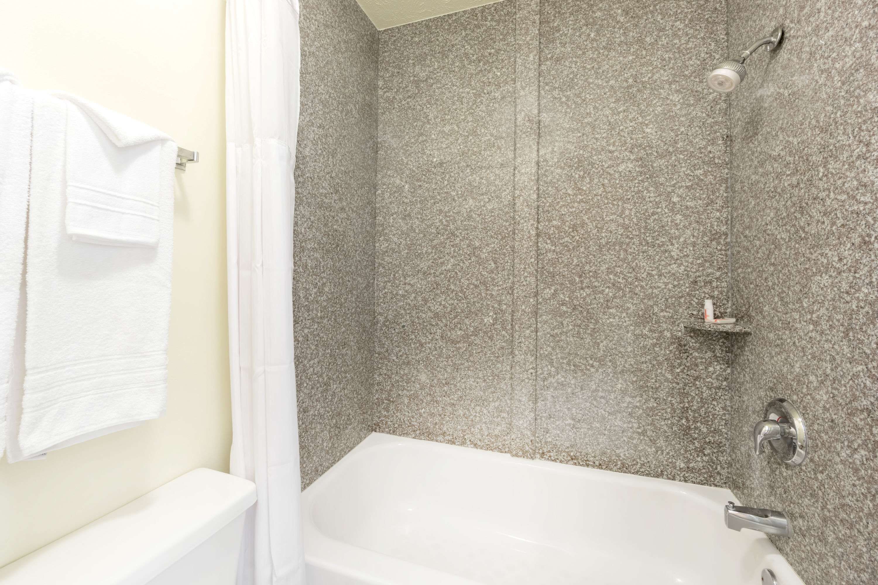 A bathroom with a white bathtub, a shower area with a glass door, and a towel rack with a white towel.