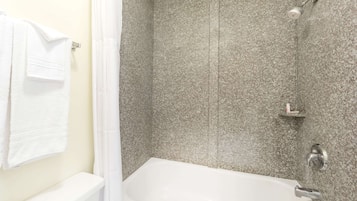 Une salle de bain avec une baignoire blanche, un espace douche doté d’une porte en verre et un porte-serviettes avec une serviette blanche.