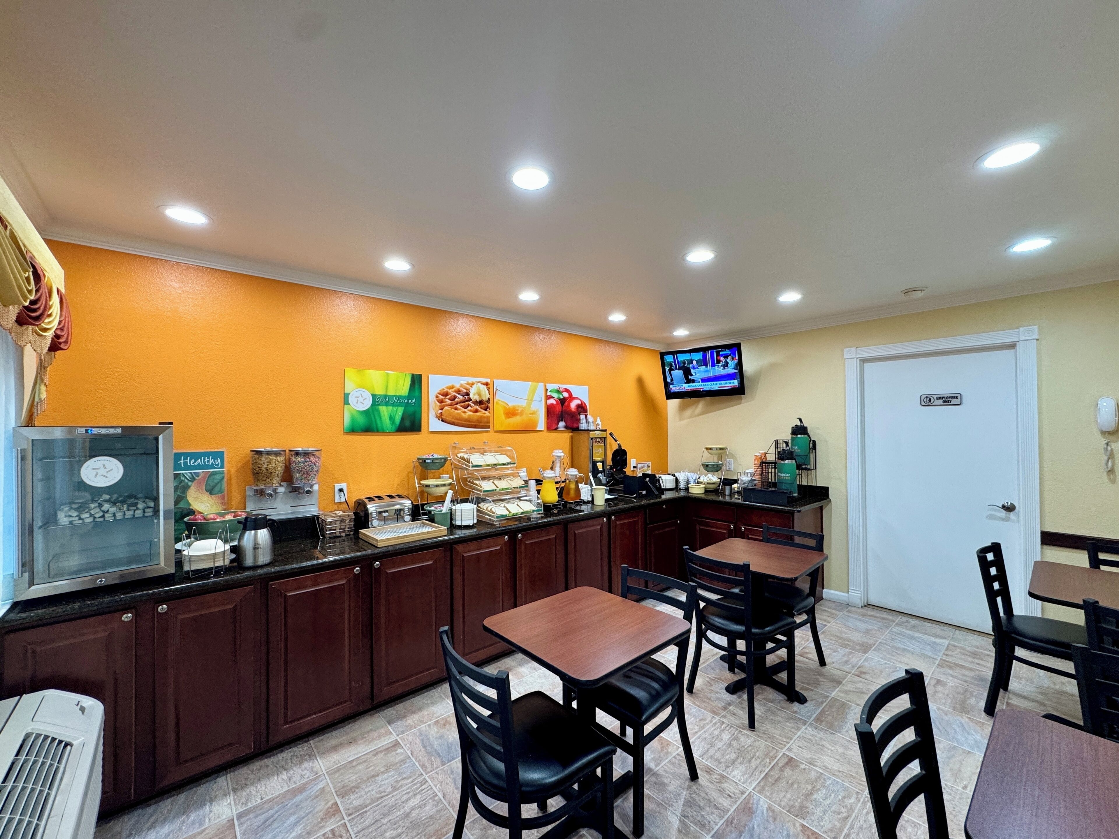 A breakfast bar with seating, a television, and a refrigerator.