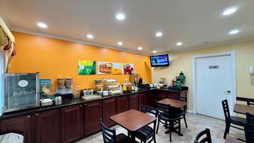 A breakfast bar with seating, a television, and a refrigerator.