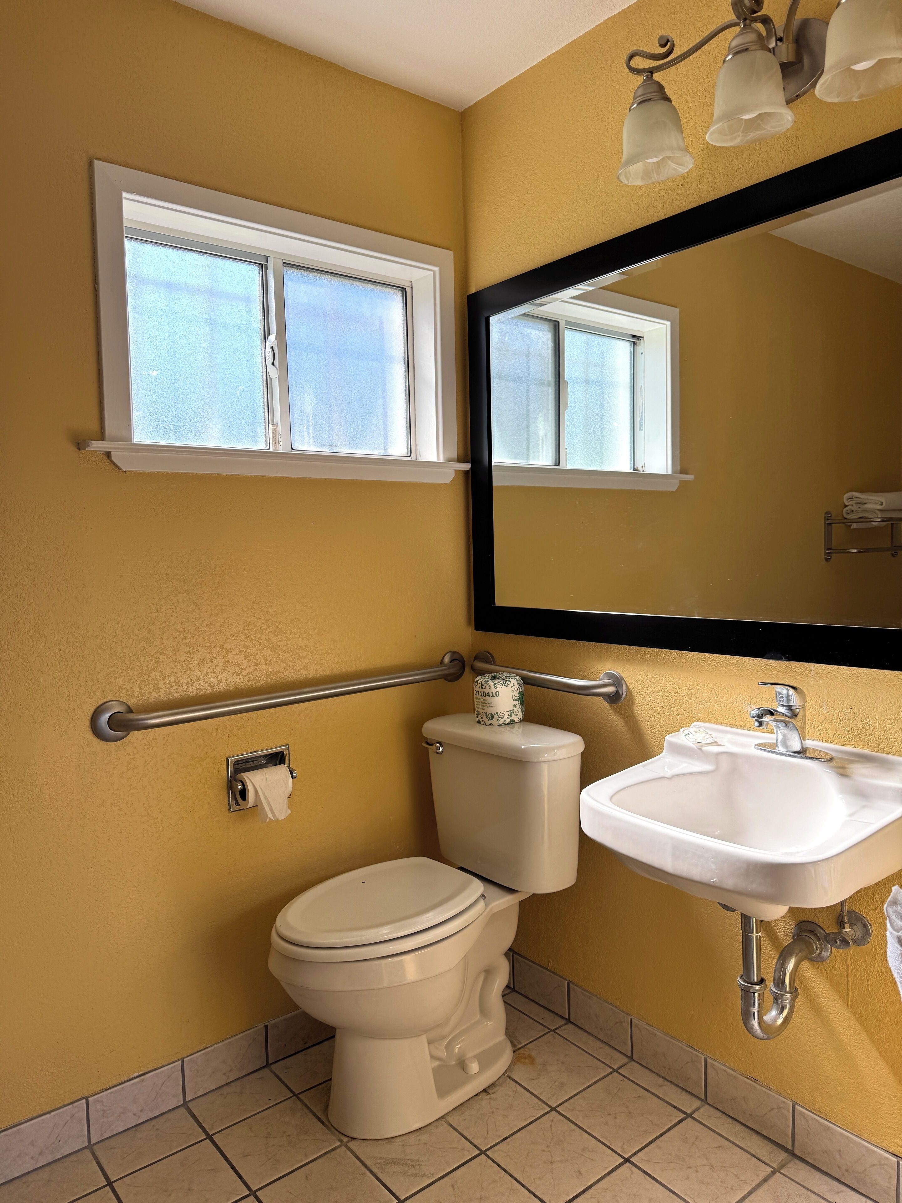 A bathroom with a toilet, sink, and a window above the toilet.