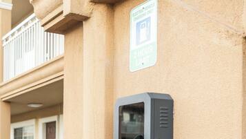 Une borne de recharge pour véhicules électriques fixée sur un mur d’immeuble, avec un panneau indiquant une durée de stationnement maximale de 2 heures.
