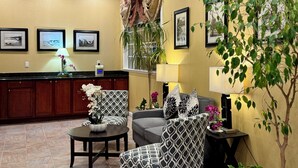A modern living room with a sofa, chairs, a coffee table, and a dining area with a counter. There are framed pictures on the wall and a potted plant. - Quality Inn Ukiah (Ukiah)