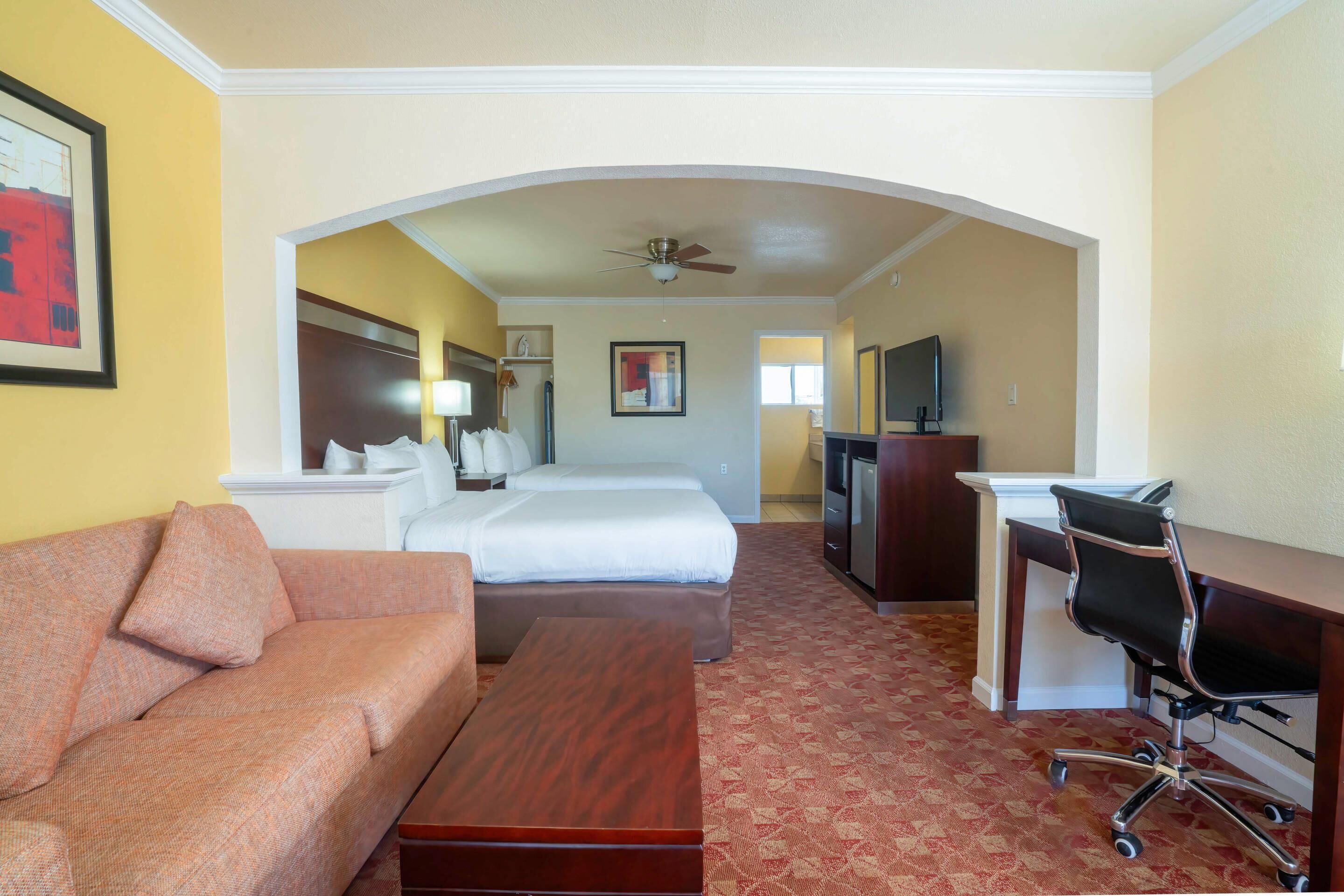 A hotel room with a sofa, a bed, a desk, and a TV.