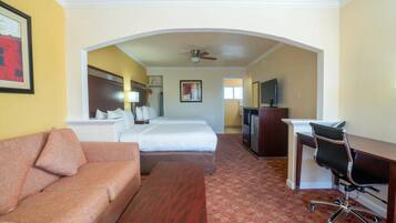 A hotel room with a sofa, a bed, a desk, and a TV.