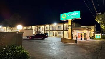 A motel with a sign reading "Quality Inn by Choice Hotels" and a parking lot with a red car.