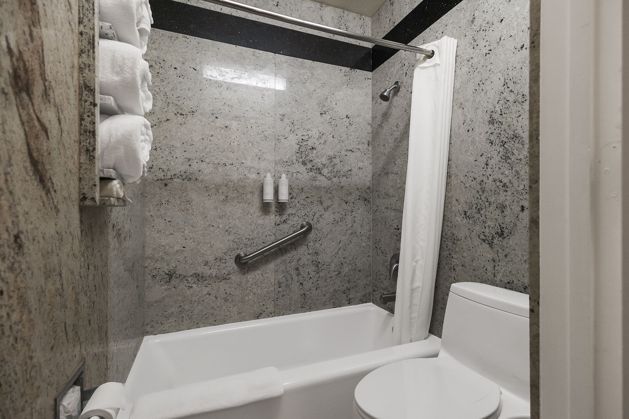 Een badkamer met douche, toilet en handdoekhouder.