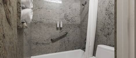 Un baño con ducha, inodoro y barra para toallas.