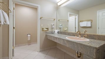 A bathroom with a granite countertop, two sinks, a large mirror, and towel racks.