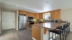 A modern kitchen with wooden cabinets, stainless steel appliances, and a granite countertop. - Country Inn Sonora (Jamestown)