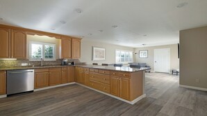 A kitchen with wooden cabinets, a built-in dishwasher, and a large island with a sink. - Country Inn Sonora (Jamestown)