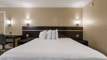 A hotel room with a large bed, two bedside tables, a chair, and wall-mounted lighting.