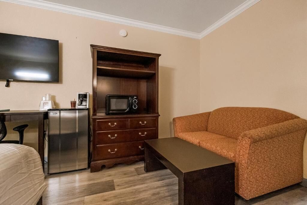 Une chambre d’hôtel compacte comprenant un coin cuisine, un téléviseur à écran plat, un canapé et une petite table.
