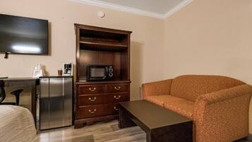 Une chambre d’hôtel compacte comprenant un coin cuisine, un téléviseur à écran plat, un canapé et une petite table.