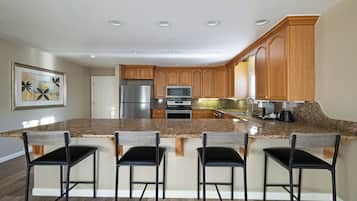 A modern kitchen with granite countertops, stainless steel appliances, and wooden cabinets.