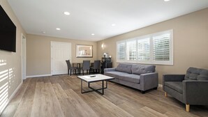 A modern living room with a grey sofa, a coffee table, and a TV mounted on the wall. - Country Inn Sonora (Jamestown)