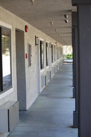 A long corridor with a series of windows and doors, likely leading to hotel rooms.
