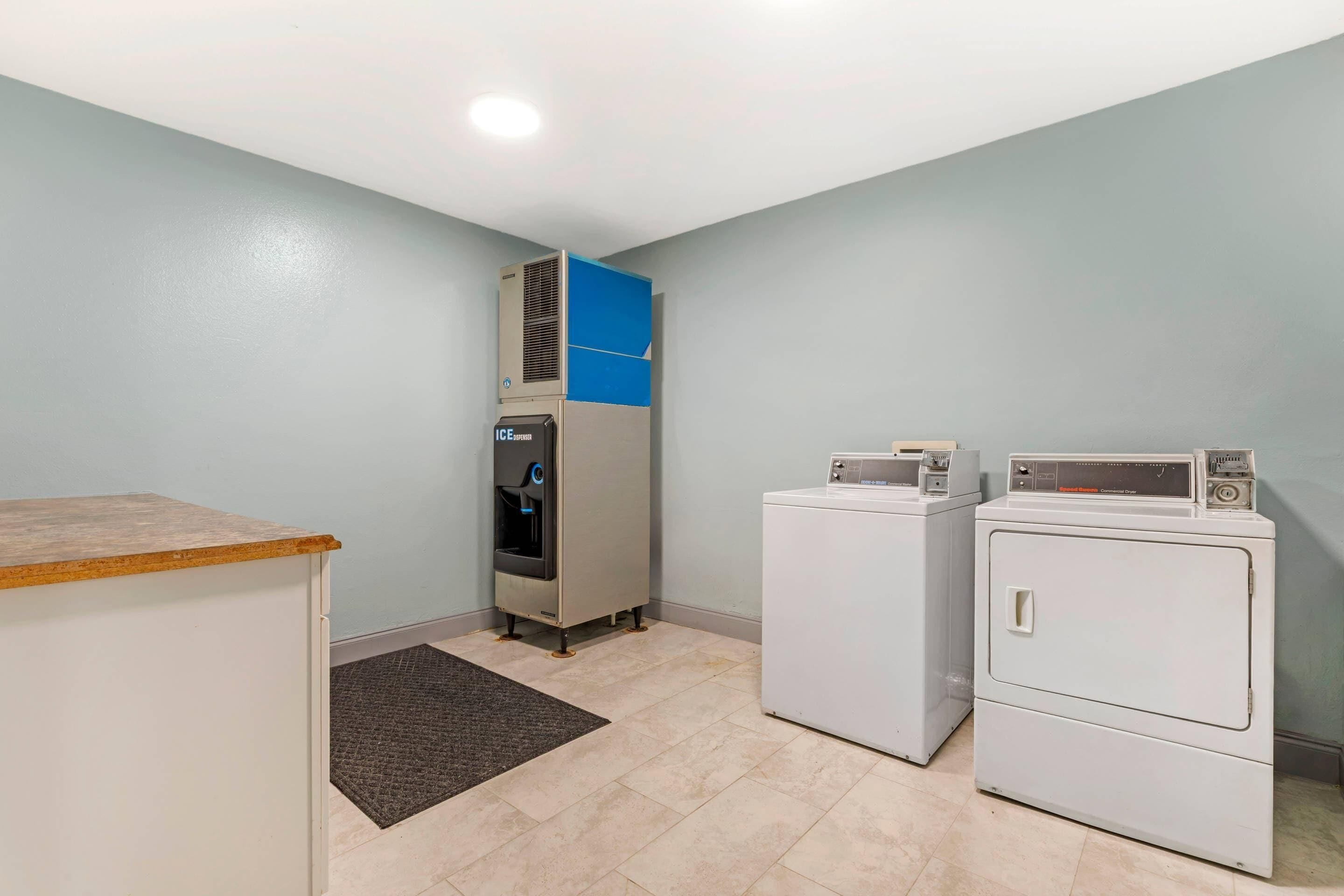 A laundry room with a water dispenser, two washing machines, and a countertop.