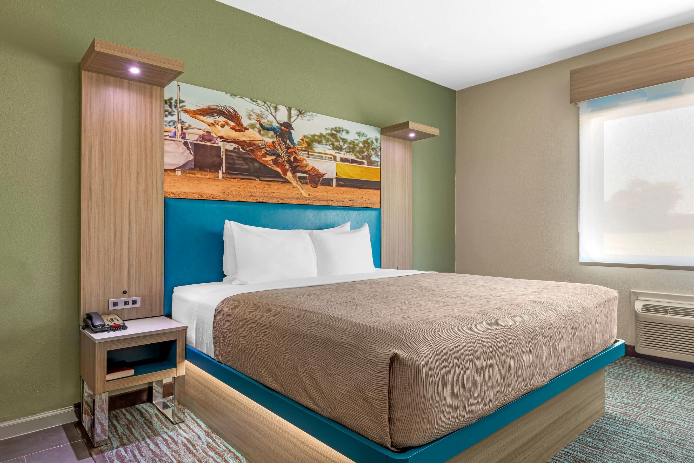 Une chambre d’hôtel avec un grand lit, une table de chevet avec un téléphone et un tableau au mur.