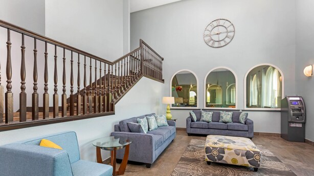 A spacious living area with a staircase, two sofas, a coffee table, and a patterned rug.