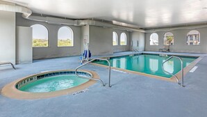 A swimming pool with a hot tub, clear water, and a tiled deck.