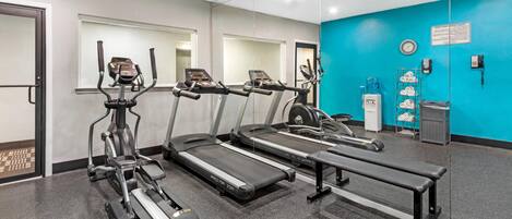 Une salle de sport équipée de tapis de course, d’un appareil elliptique et d’un banc de musculation.
