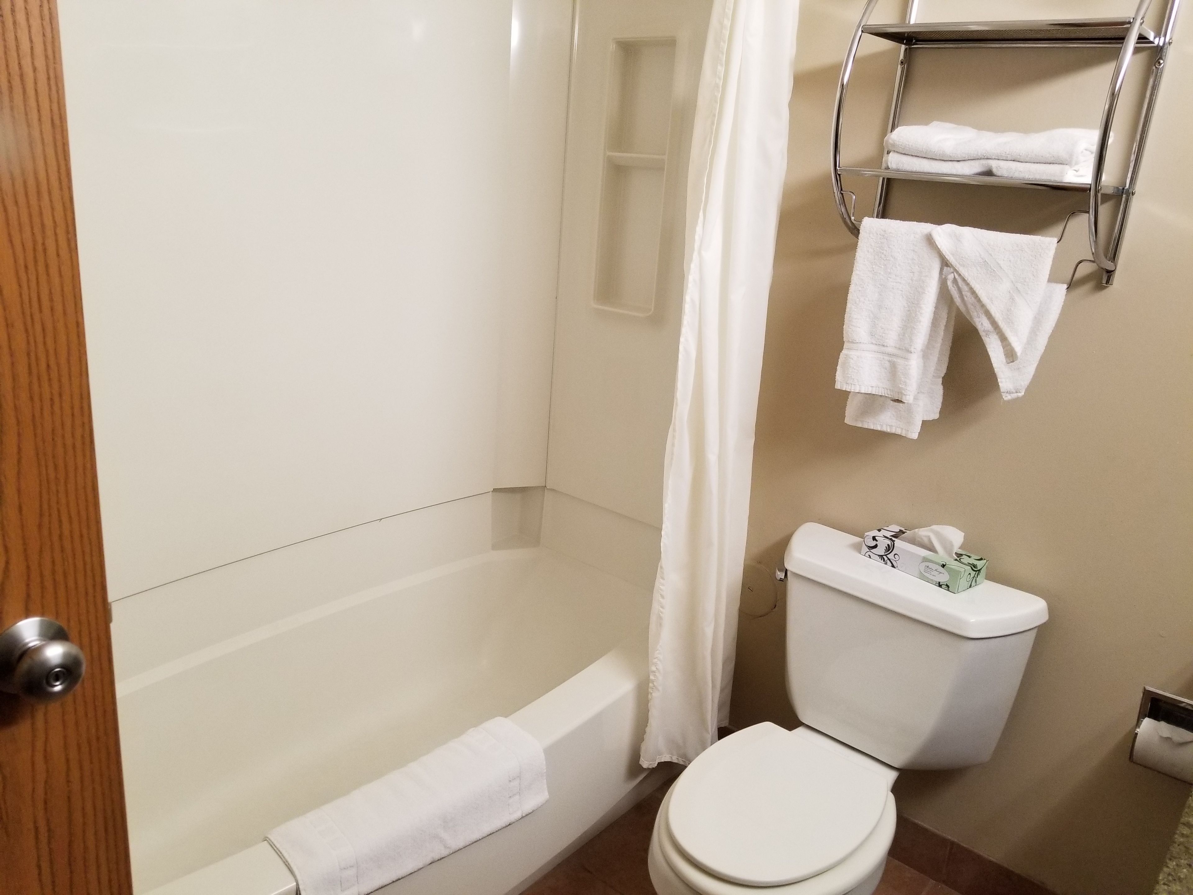 A bathroom with a bathtub, toilet, and a towel rack with towels.