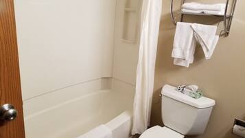 A bathroom with a bathtub, toilet, and a towel rack with towels.