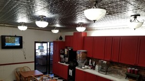 Un restaurante con armarios rojos, piso a cuadros y un televisor en la pared.