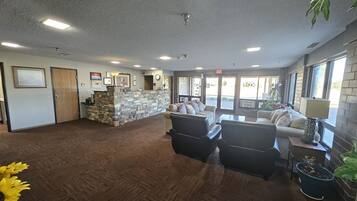 A lobby with a reception desk, seating area, and large windows.