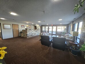 A lobby with a reception desk, seating area, and large windows.