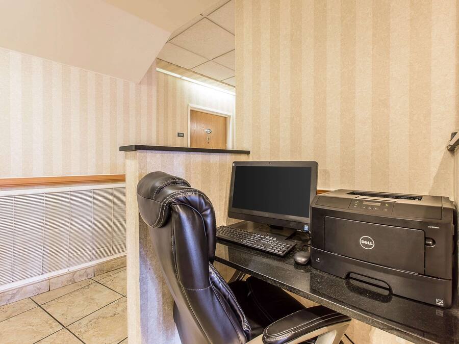 A hotel room with a desk, computer, and printer.