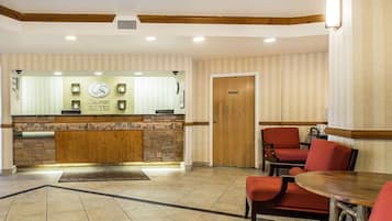 A reception area with a stone counter, red seating, and a wooden door.