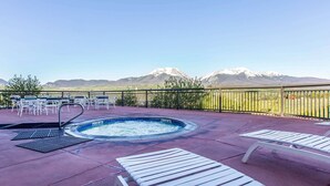 A rooftop pool area with lounge chairs, a hot tub, and a view of snow-capped mountains. - Comfort Suites Summit County (Dillon)