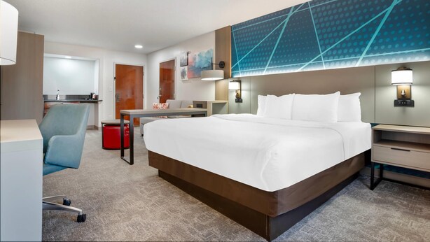 A modern hotel room with a large bed, a desk, a chair, and a small table. - Comfort Inn Livingston (Livingston)